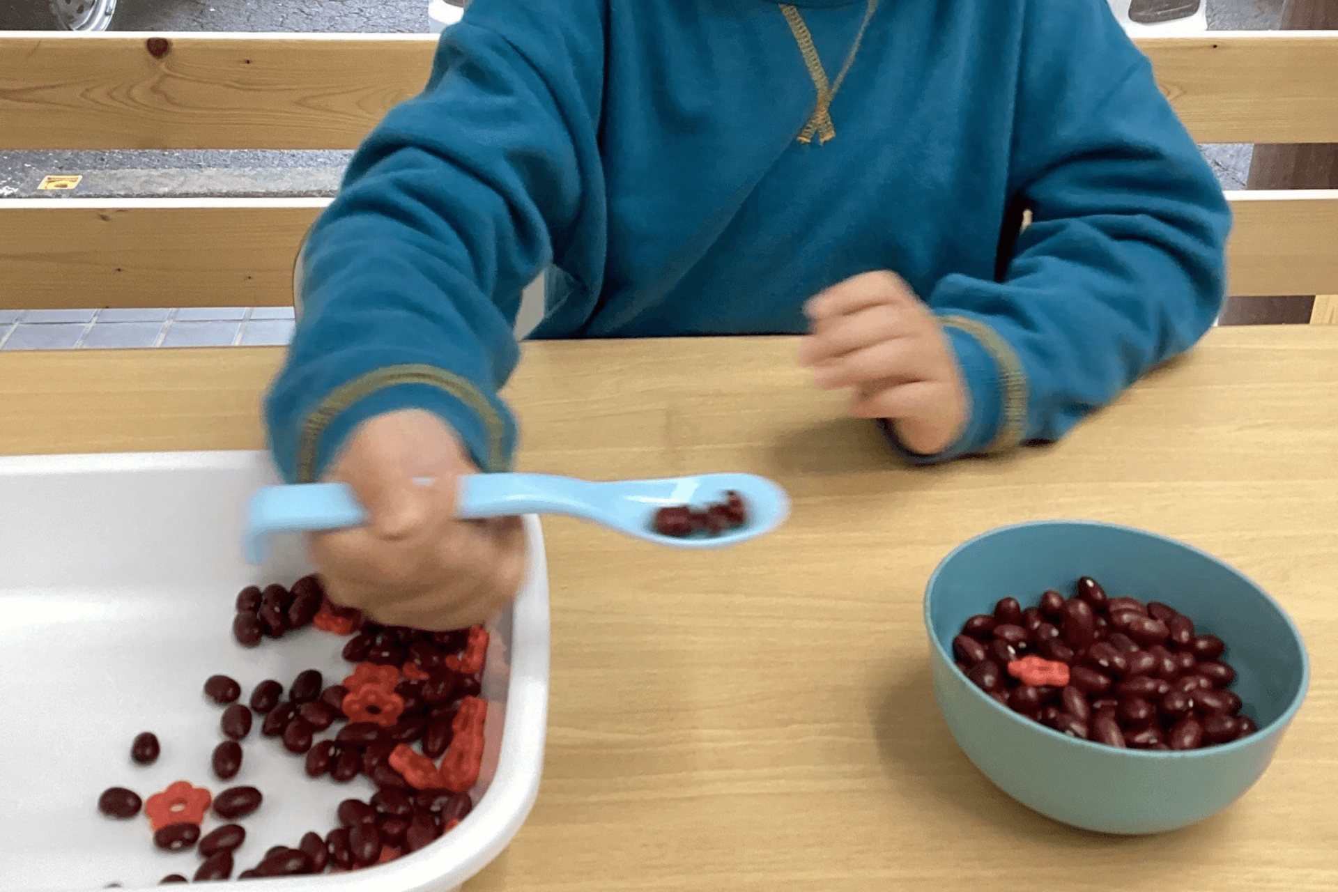 小さな男の子がスプーンで食べる練習をしている